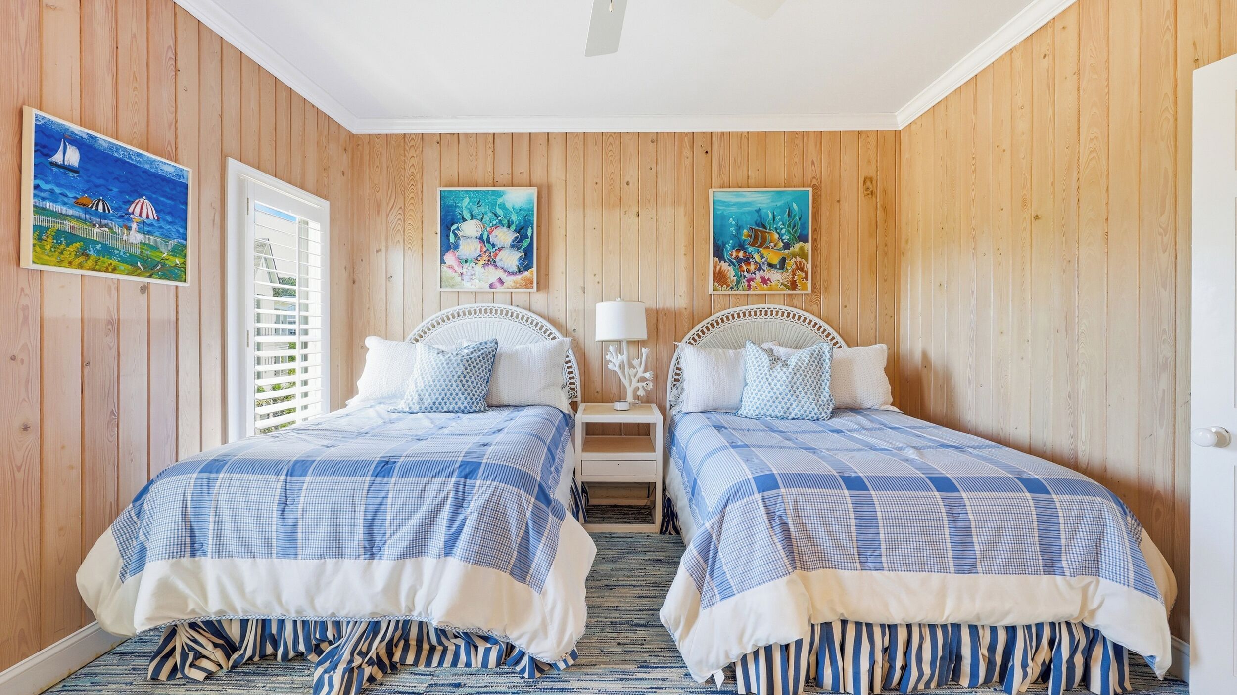 A double room with two beds, wooden paneling, and artwork on the walls.
