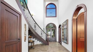 A hallway with a wooden door, a staircase, and a large window.