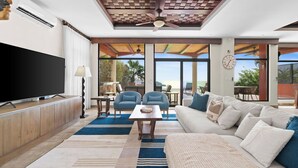 A modern living room with a flat-screen TV, a ceiling fan, a sofa, and a coffee table.