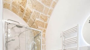 Ein Badezimmer mit Duschkabine, Toilette, Bidet und Waschtisch mit Spiegel.