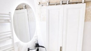 Ein Badezimmer mit einem weißen Waschbecken, einem Spiegel, einem Handtuchhalter und einem Bidet.