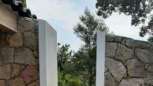 Un mur de pierre avec une terrasse en bois qui mène à un jardin.