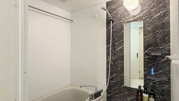Combined shower/bathtub, hair dryer, slippers, towels