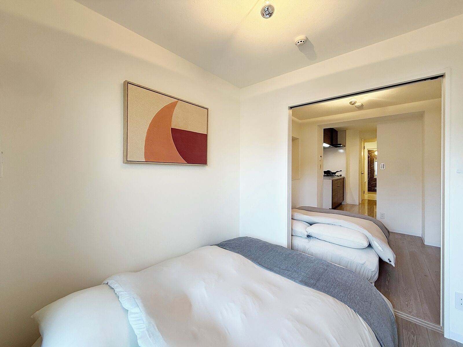 A bedroom with a bed, a mirror, and a painting on the wall.