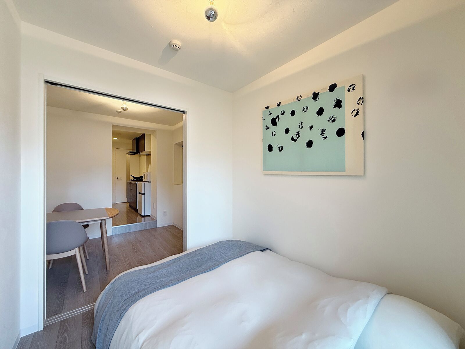 A bedroom with a bed, a desk, and a kitchenette.