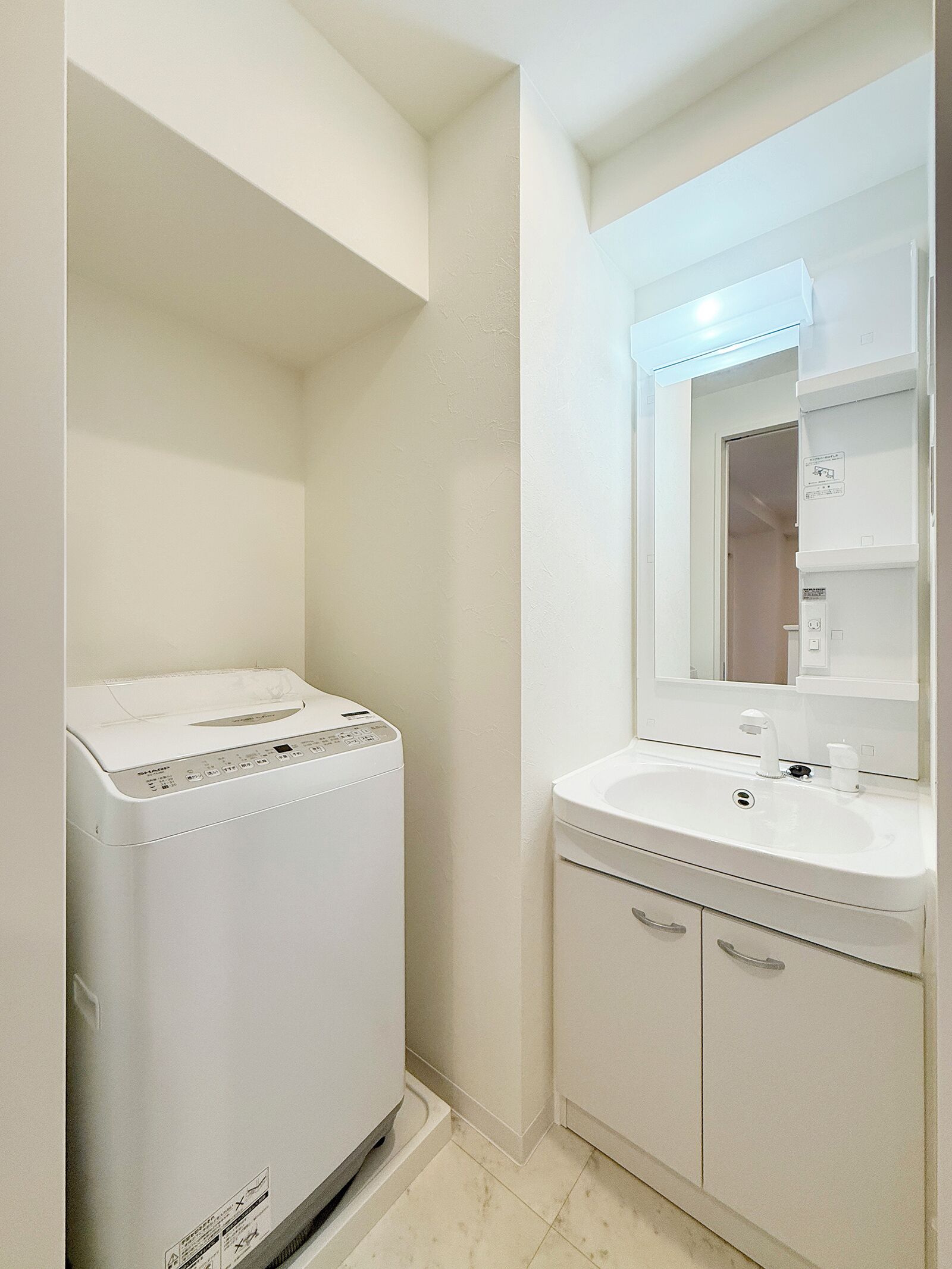 Un baño pequeño con lavadora, lavamanos y espejo.