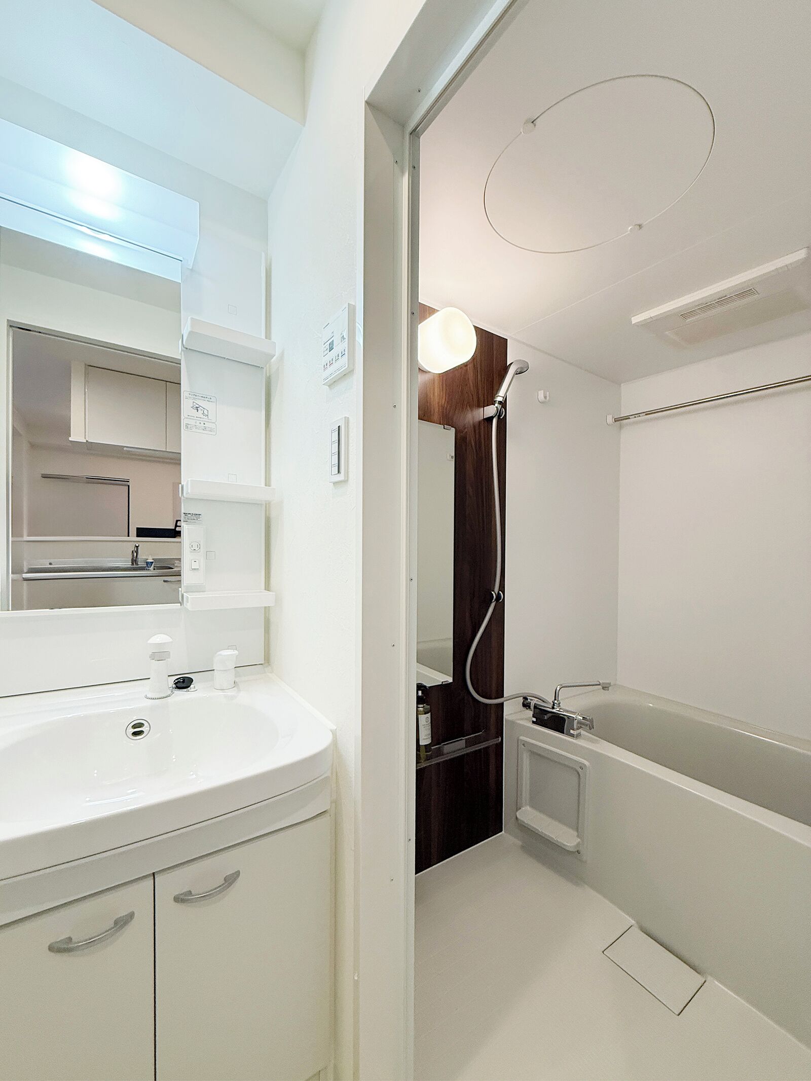 Un baño moderno con lavamanos, espejo y ducha blancos.