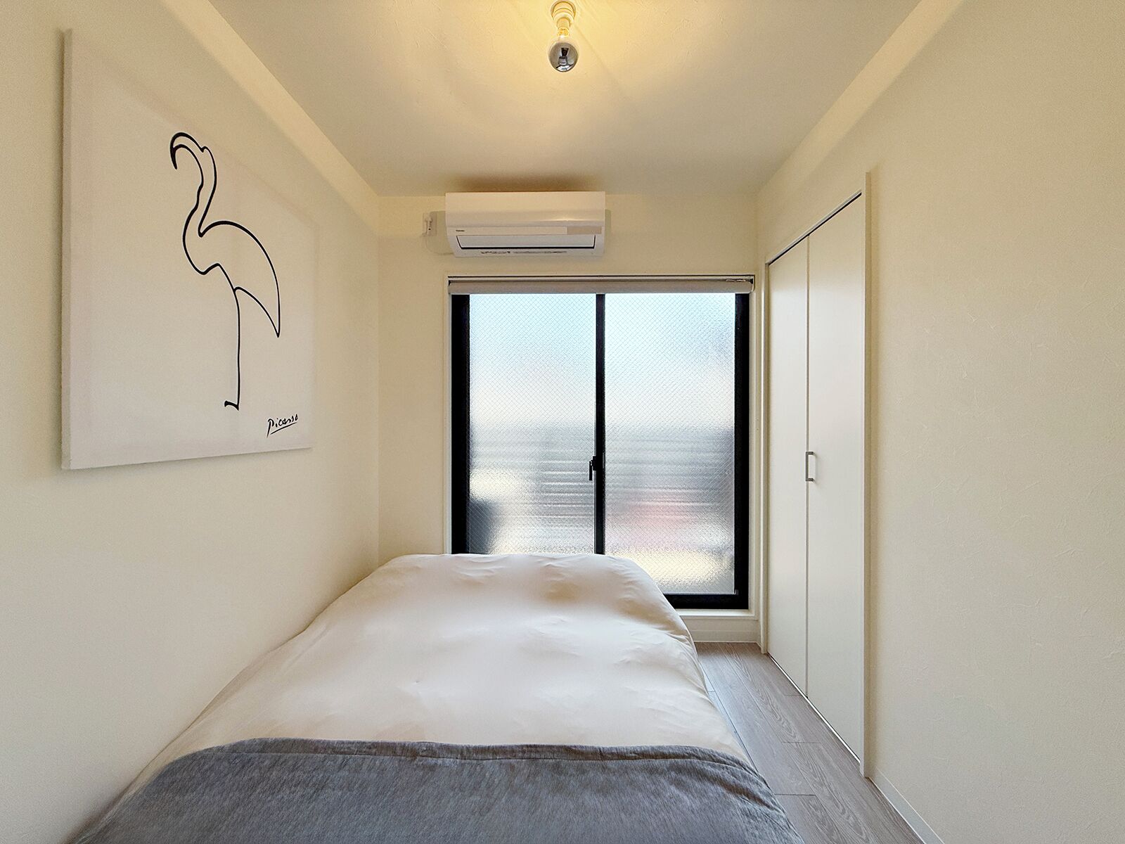 Une chambre à coucher avec un lit, un climatiseur fixé au mur, une porte et une fenêtre donnant sur un paysage agréable.