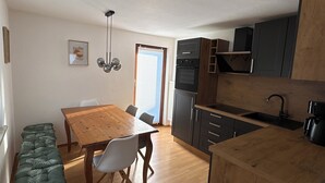 Uma cozinha compacta com uma mesa de madeira, cadeiras, um banco e eletrodomésticos embutidos.