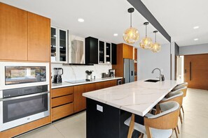 A modern kitchen with a central island, built-in appliances, and pendant lighting.