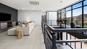Ein modernes Wohnzimmer mit großem Fernseher, einer Couch und einem Essbereich mit Bergblick.