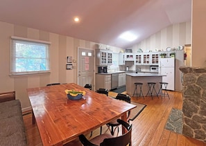 Una cocina con armarios blancos, una mesa de comedor de madera y una pared decorativa de piedra.