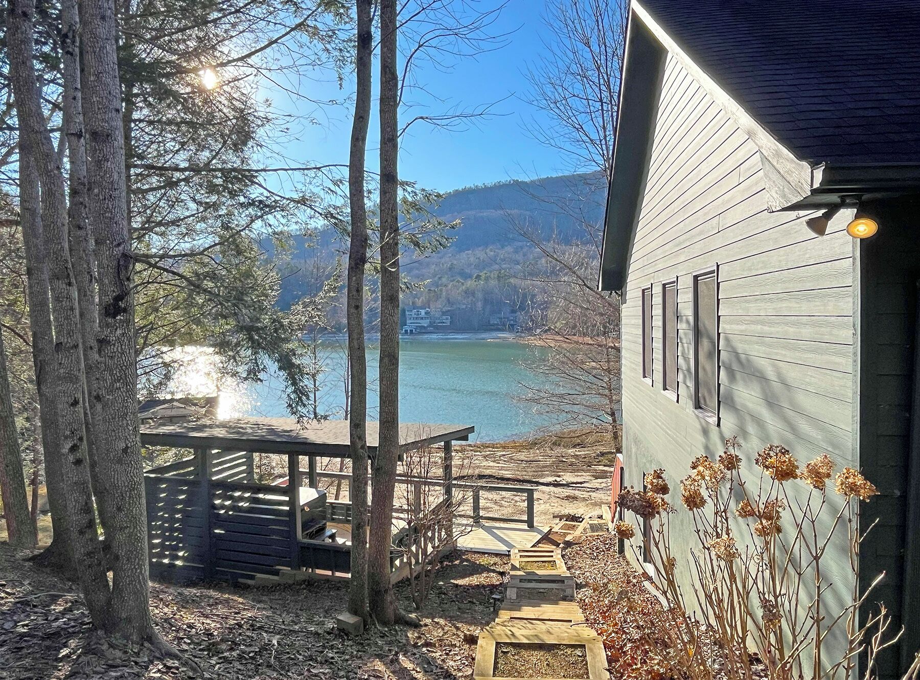 A cabin with a deck overlooking a lake, surrounded by trees.