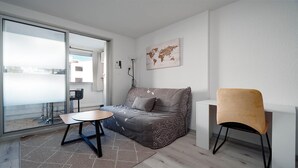 A modern, minimalistic room with a sofa, a small round table, a chair, and a world map on the wall. - Sophisticated Retreat Near the Sea, Agde (Agde)