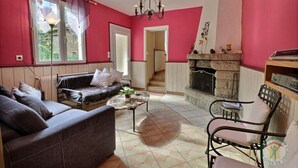 A living room with a fireplace, a sofa, a coffee table, and a chair. - The Monthorin Valley (La Bazouge-du-Désert)