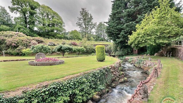 A garden with a stream, a circular flower bed, and a hedge. - The Monthorin Valley (La Bazouge-du-Désert)