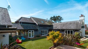 A house with a sloped roof, a covered patio, and a lawn. - Some homes are made for holidays,  Surfers Roost is made for time well spent together. (Croyde)