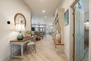 A hallway with a dining area, a clock, a lamp, and a door leading to another room. - "Tivoli Palms" New Reno! Sandestin, Golf Cart, Pool, Golf Course, Beach (Miramar Beach)