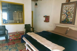 Una camera da letto con un letto, una sedia, una scrivania e un tappeto colorato.