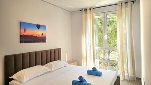 Une chambre d’hôtel avec un lit, un tableau représentant des montgolfières et une fenêtre avec des rideaux.