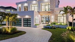Una moderna casa a due piani con garage, ampie finestre e un giardino curato.