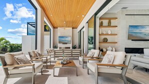 Un soggiorno moderno con soffitto in legno, un televisore grande e vista sull'esterno.