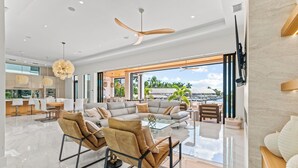 Un'ampia zona giorno con un divano moderno, un tavolino in vetro e una ventola a soffitto.