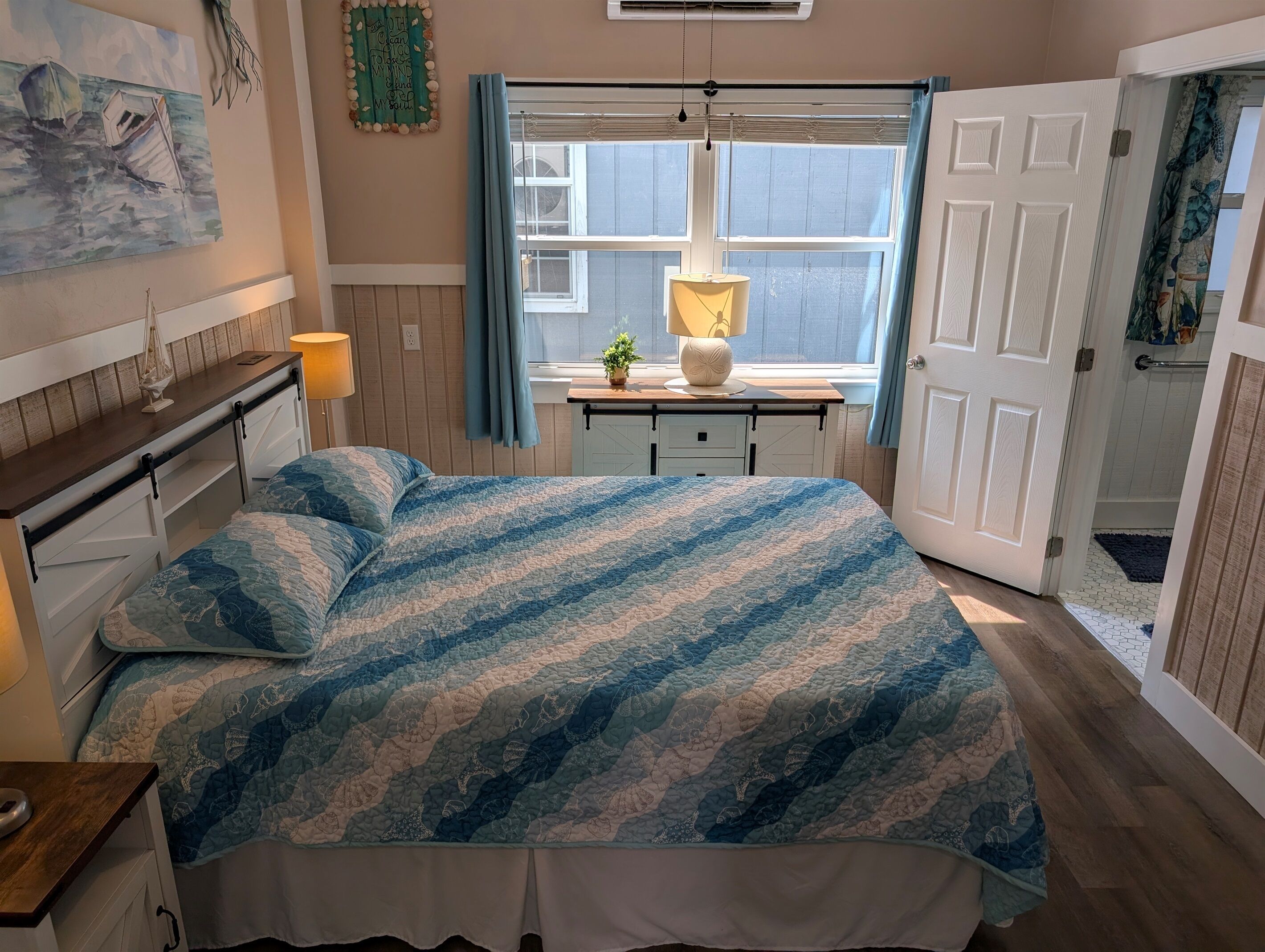 A bedroom with a bed, bedside tables, a window, a door, and a wall decoration.