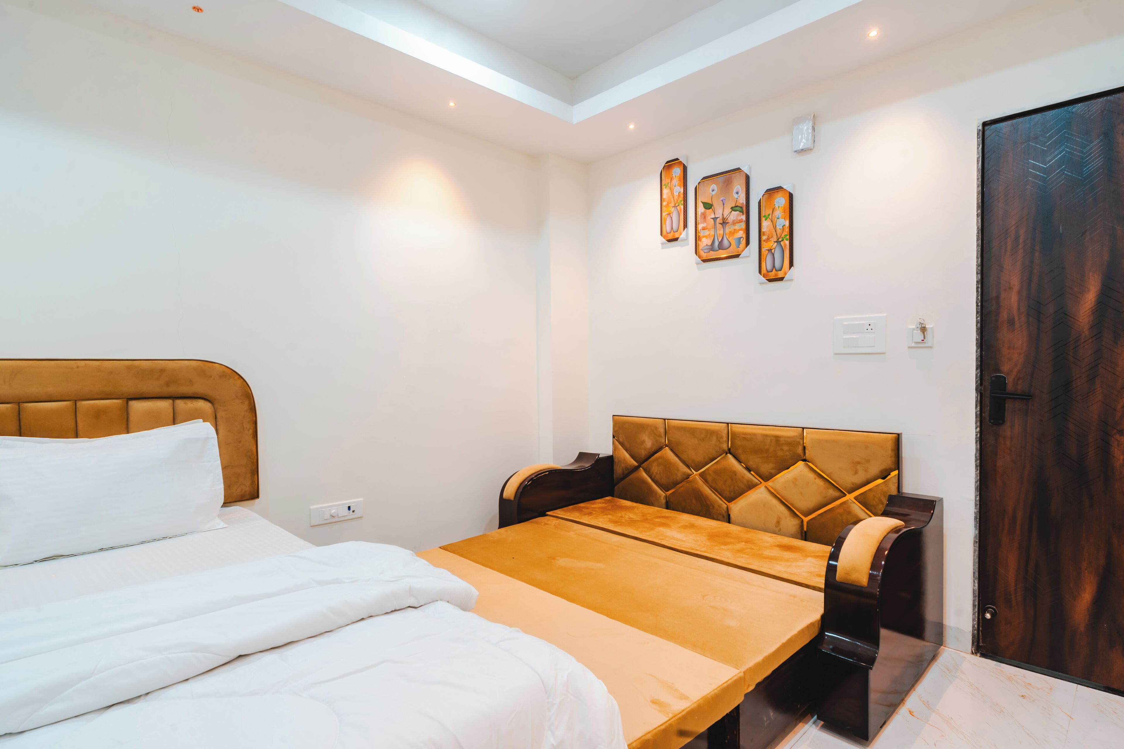 A hotel room with a bed, a sofa, a small table, and a wooden door.