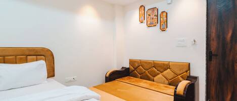 A hotel room with a bed, a sofa, a small table, and a wooden door.