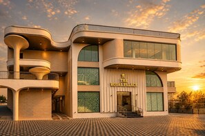 Un bâtiment moderne à la façade incurvée, doté de grandes fenêtres et d’une enseigne indiquant « Le Palais Royal ».