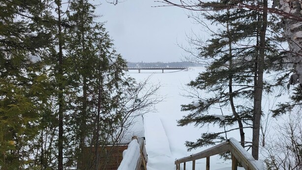 A snowy pathway leading to a bridge, surrounded by evergreen trees. - Superb cottage with view and privileged access to Preissac Lake - Pets allowed (Preissac)