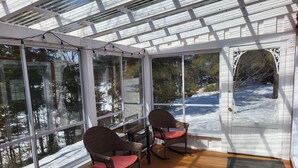 A sunroom with large windows, wicker chairs, and a view of a snowy landscape. - Superb cottage with view and privileged access to Preissac Lake - Pets allowed (Preissac)