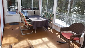 A sunroom with a table and chairs, large windows, and a view of trees. - Superb cottage with view and privileged access to Preissac Lake - Pets allowed (Preissac)