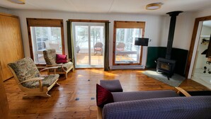 A cozy living room with wooden floors, a fireplace, and a large sliding glass door leading to an outdoor patio. - Superb cottage with view and privileged access to Preissac Lake - Pets allowed (Preissac)