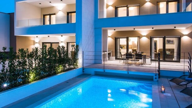 Un hôtel moderne doté d’une piscine, d’un espace extérieur aménagé et d’un balcon bien éclairé.