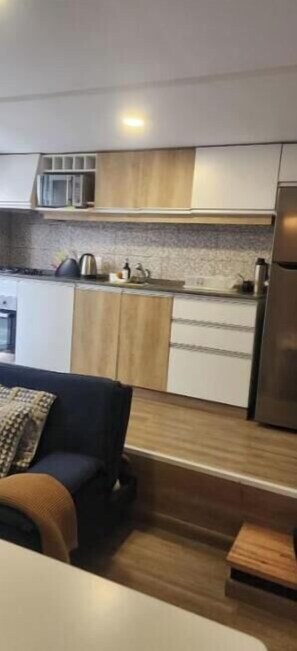 A modern kitchen with wooden cabinets, a microwave, and a refrigerator. - Beautiful duplex in Montevideo (pet friendly) (Montevideo)