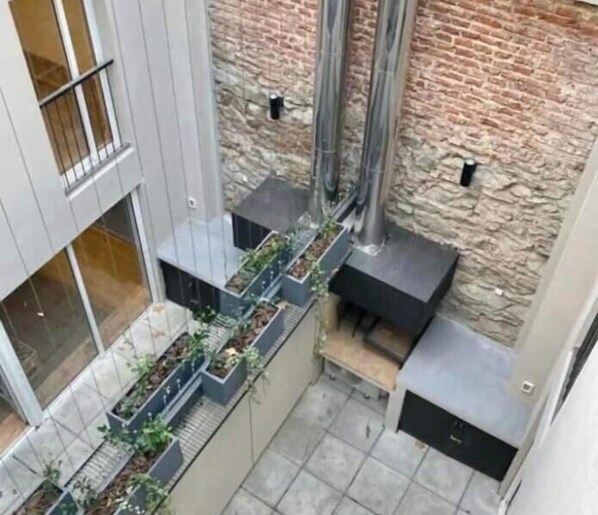A modern outdoor space with a brick wall, metal structures, and a planter with plants. - Beautiful duplex in Montevideo (pet friendly) (Montevideo)