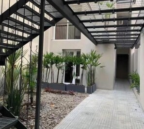 A covered outdoor area with a metal staircase, potted plants, and a tiled walkway. - Beautiful duplex in Montevideo (pet friendly) (Montevideo)