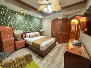 Ein Hotelzimmer mit Bett, Holzschrank, Nachttisch, Lampe und Deckenventilator.