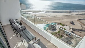 A balcony with a view of a beach and a pool. - Beachfront 1BR High-floor Panoramic Views (Puerto Peñasco)