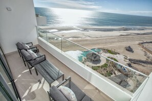 A balcony with a view of a beach and a pool. - Beachfront 1BR High-floor Panoramic Views (Puerto Peñasco)