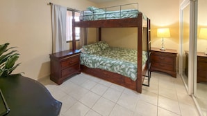 Ein Zimmer mit einem Etagenbett, einem Schreibtisch mit Schubladen, einer Lampe und einem Blumentopf.