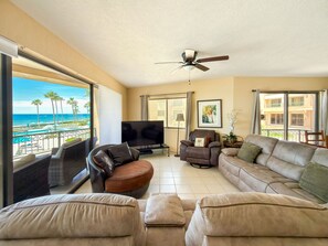 A living room with a view of the beach, a ceiling fan, a flat-screen TV, and a sofa. - Relaxing Oceanview Condo Pools Beach (Puerto Peñasco)