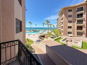 A hotel with a pool, palm trees, and a view of the ocean. - Relaxing Oceanview Condo Pools Beach (Puerto Peñasco)