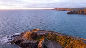 A coastal landscape with a stone pathway leading to a cliff edge overlooking the sea. - Spacious Countryside Home Yoga Studio (Haverfordwest)