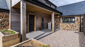 A wooden building with a stone exterior, a covered porch, and a gravel driveway. - Spacious Countryside Home Yoga Studio (Haverfordwest)