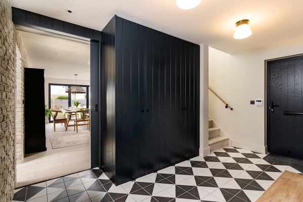 A modern interior with a geometric patterned floor, a dark wooden wardrobe, and a staircase leading to another level. - Spacious Countryside Home Yoga Studio (Haverfordwest)