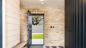 A hallway with a wooden bench, a black door, and a view of a grassy area through a glass door. - Spacious Countryside Home Yoga Studio (Haverfordwest)