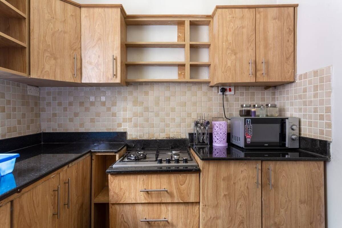 A kitchen with wooden cabinets, a gas stove, a microwave, and a tiled backsplash.